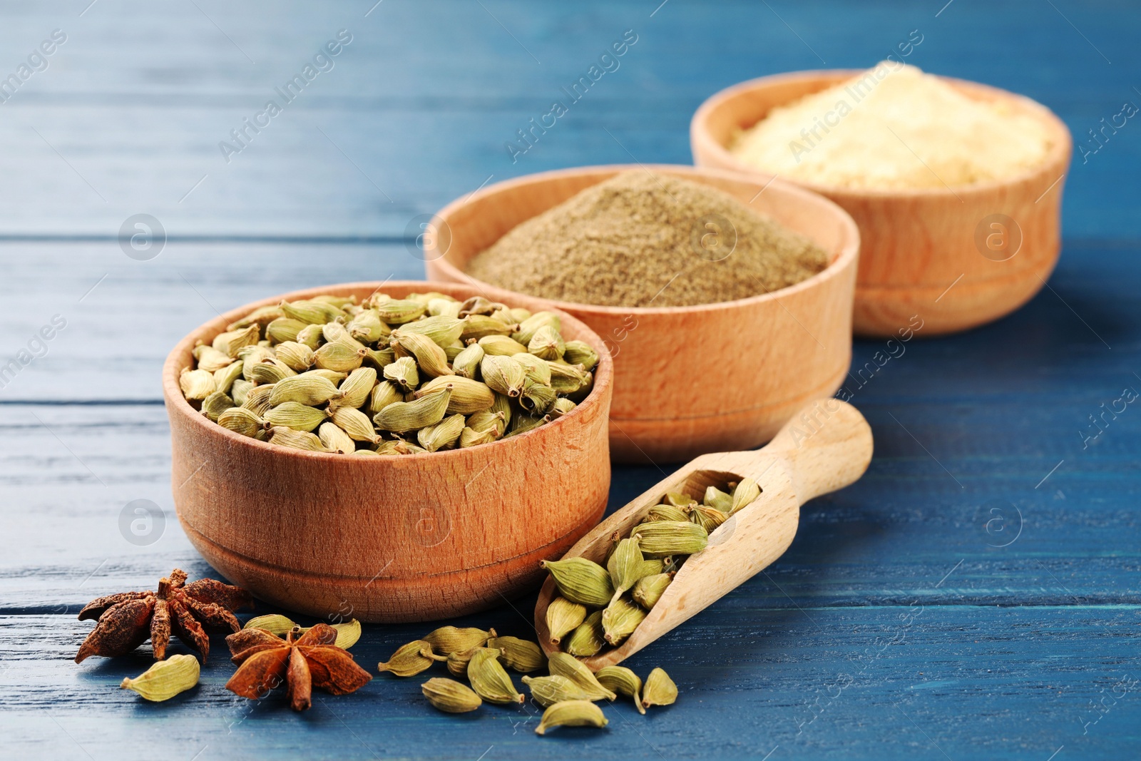 Photo of Different spices on blue wooden table, focus on cardamom