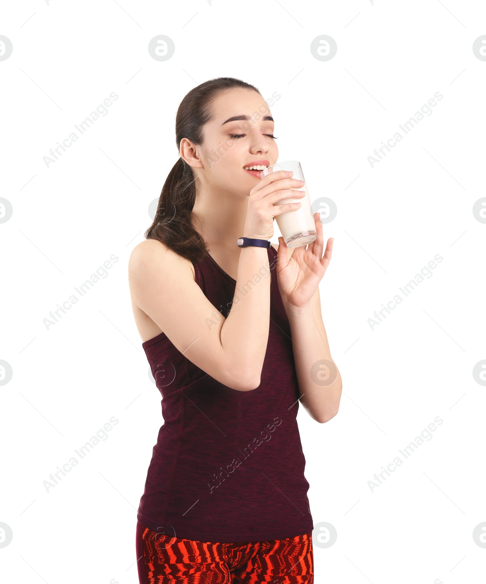 Photo of Beautiful young woman in sportswear drinking milk on white background