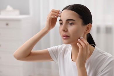 Photo of Woman with dry skin checking her face indoors
