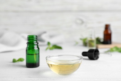 Bowl and bottle of essential oil on table. Space for text