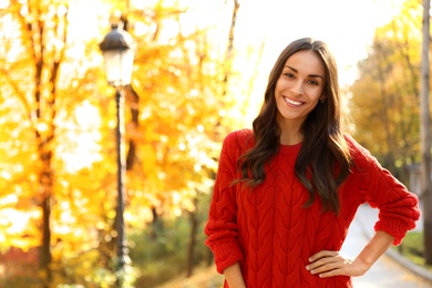 Beautiful woman wearing red sweater in sunny park. Autumn walk