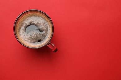 Photo of Fresh coffee in cup on red background, top view. Space for text