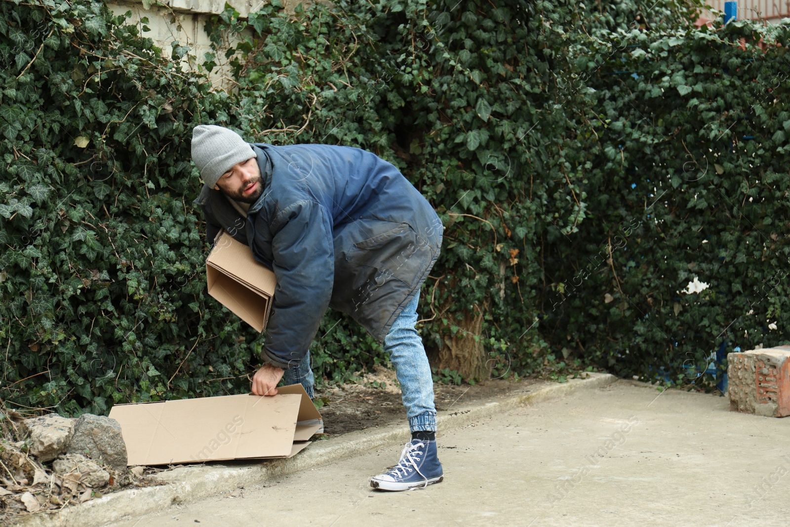 Photo of Poor homeless man with cardboard on street