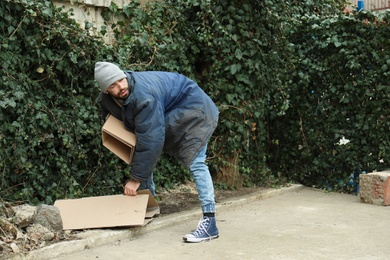 Poor homeless man with cardboard on street