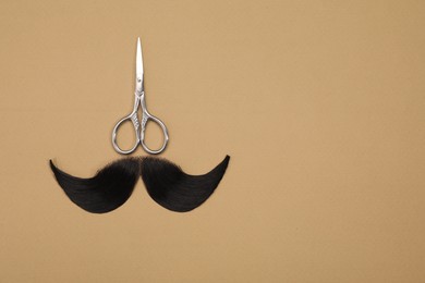 Photo of Artificial moustache and scissors on beige background, top view. Space for text