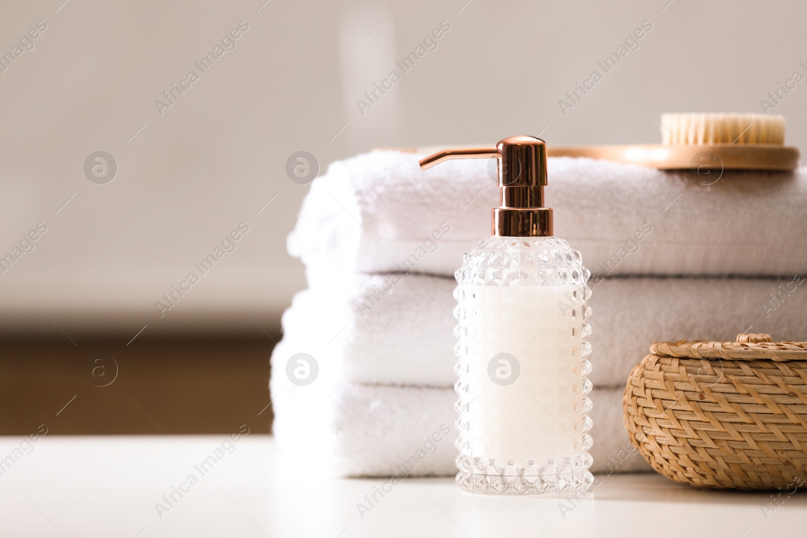 Photo of Composition with soap dispenser and towels on white table indoors. Space for text