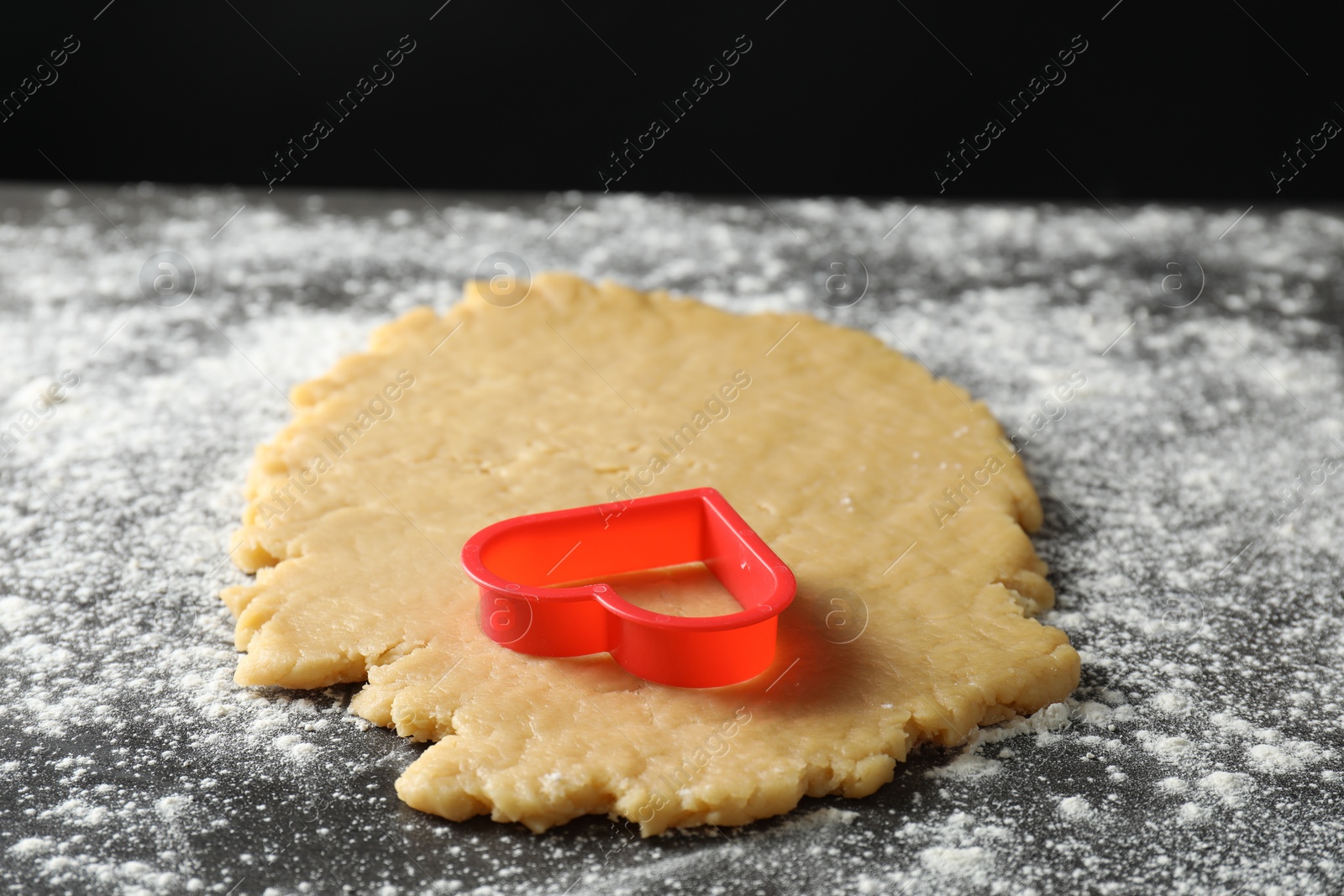 Photo of Making shortcrust pastry. Raw dough and cookie cutter on grey table