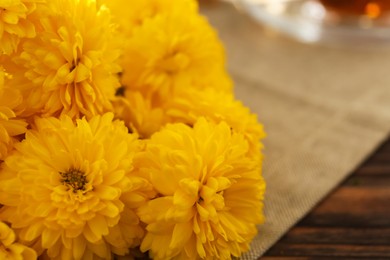 Beautiful yellow chrysanthemum flowers on wooden table, closeup. Space for text