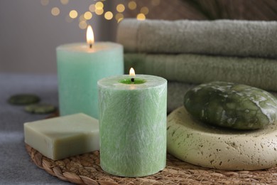 Photo of Spa composition. Burning candles, stone, soap and towels on grey table