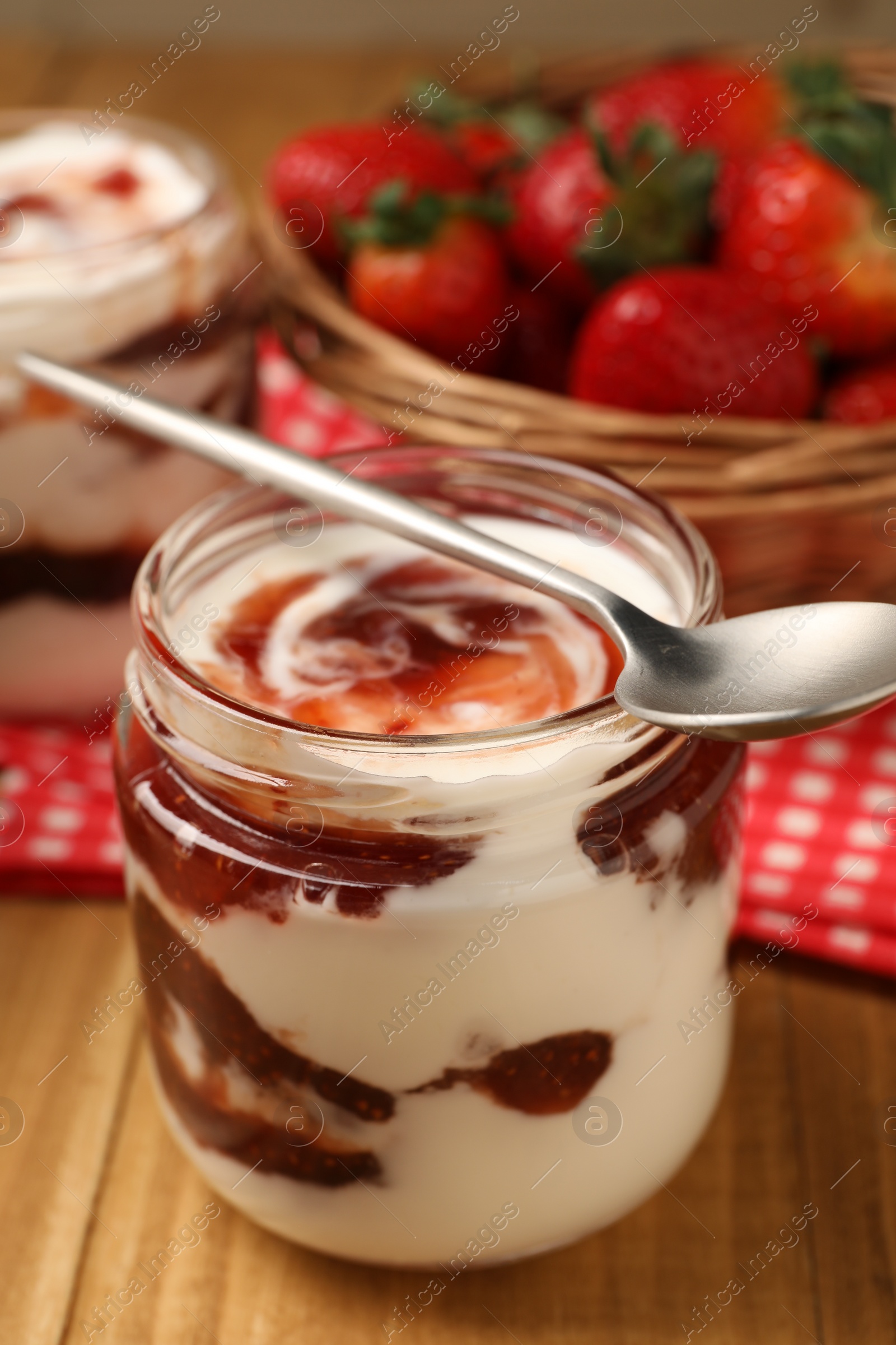 Photo of Tasty yoghurt with jam and strawberries on wooden table, closeup