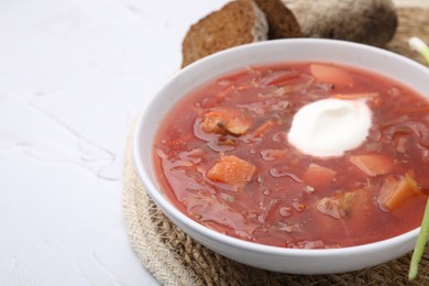 Photo of Tasty borscht with sour cream on white table, closeup. Space for text