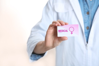 Photo of Doctor holding medical business card isolated on white, closeup. Women's health service