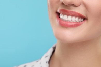 Photo of Woman with clean teeth smiling on light blue background, closeup. Space for text