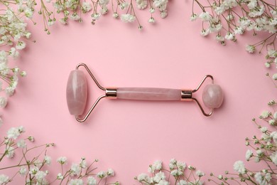 Photo of Natural face roller and flowers on pink background, flat lay