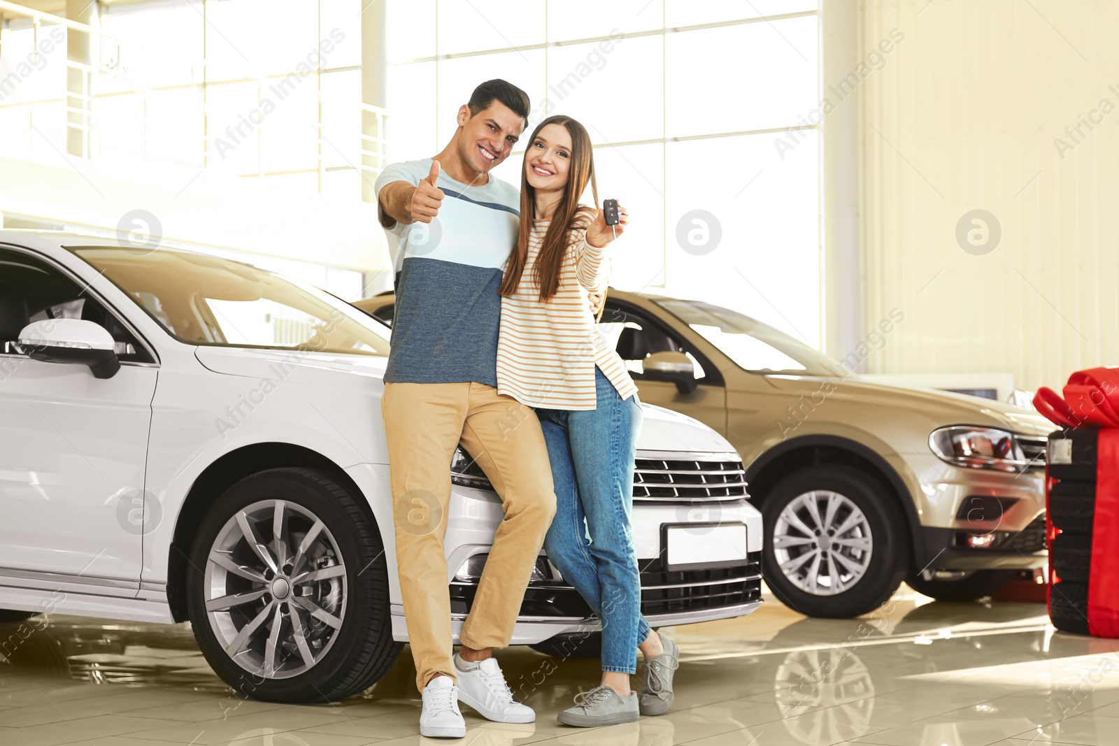 Photo of Happy couple with car key in modern auto dealership