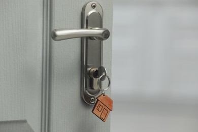 Key with house shaped fob in door lock, closeup. Space for text