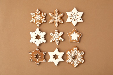 Photo of Christmas snowflake shaped gingerbread cookies on brown background, flat lay