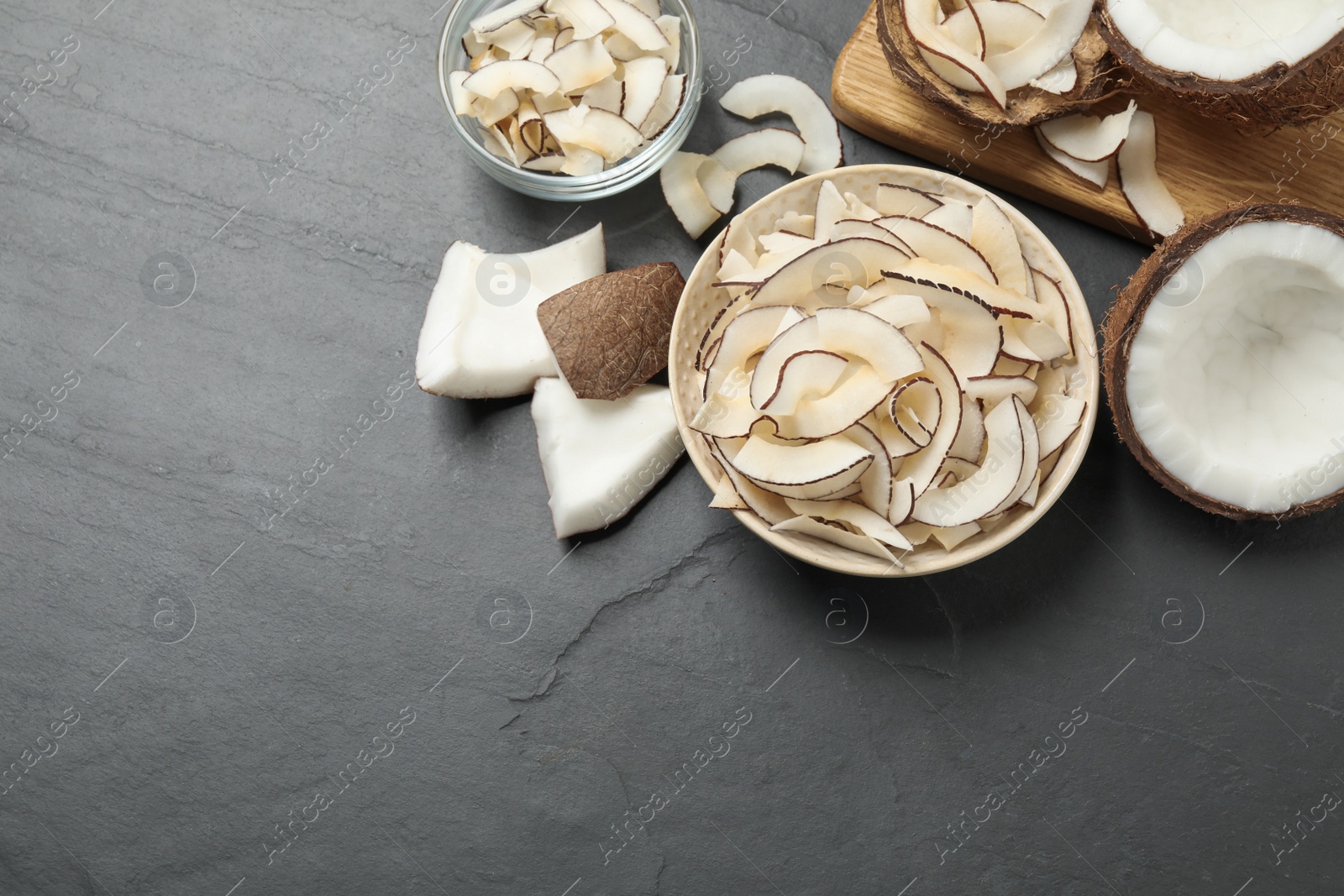 Photo of Flat lay composition with tasty coconut chips on black table. Space for text
