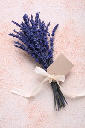 Photo of Bouquet of beautiful preserved lavender flowers with blank tag and ribbon on color textured table, top view. Space for text