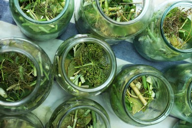 Photo of Glass jars with different herbs on table, flat lay. Pickling vegetables