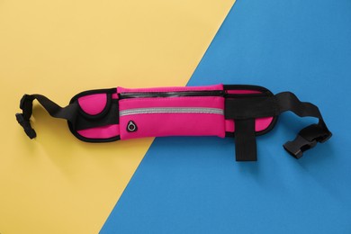 Photo of Stylish pink waist bag on color background, top view