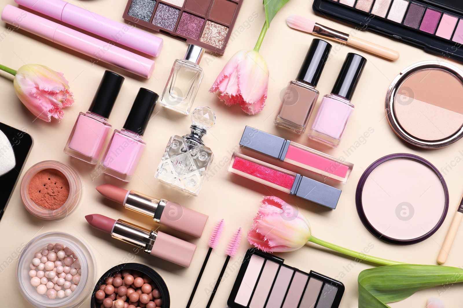 Photo of Flat lay composition with different makeup products and beautiful spring flowers on beige background