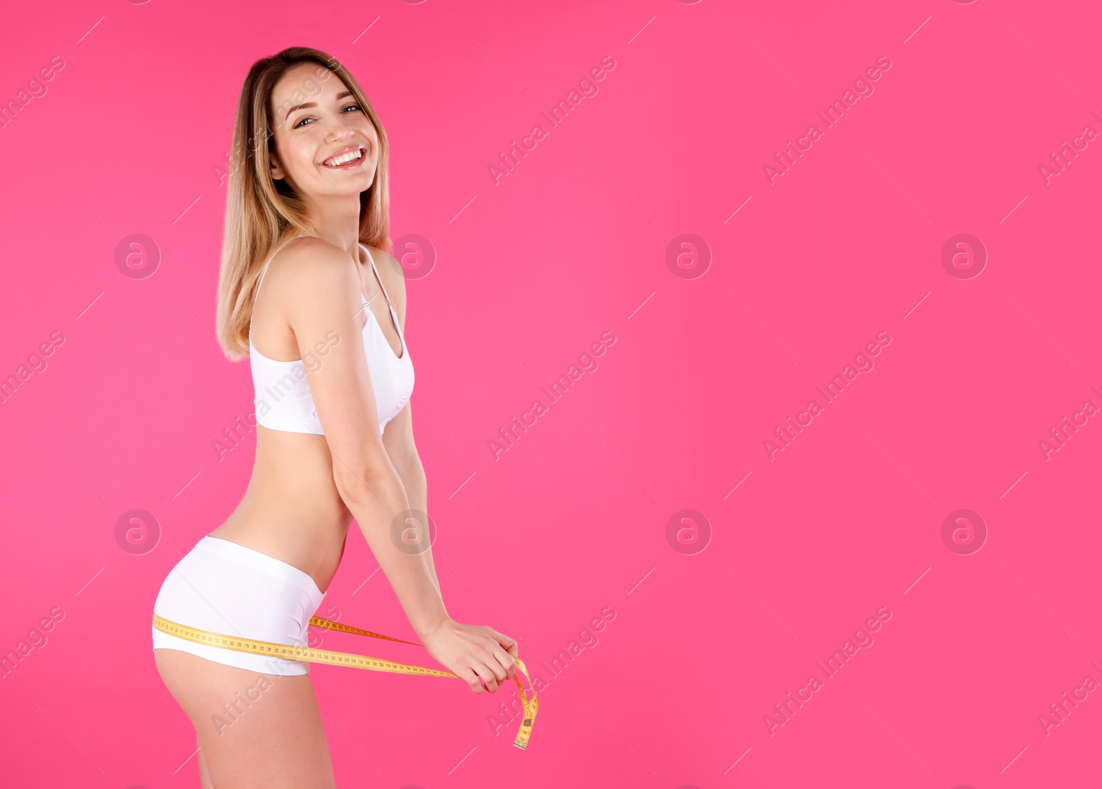 Photo of Slim woman measuring her hips on color background, space for text. Perfect body