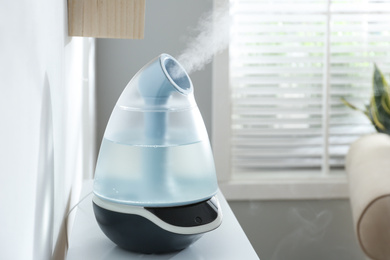 Modern air humidifier on table at home. Space for text