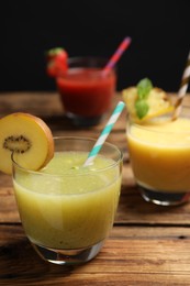 Photo of Delicious colorful juices in glasses on wooden table, closeup