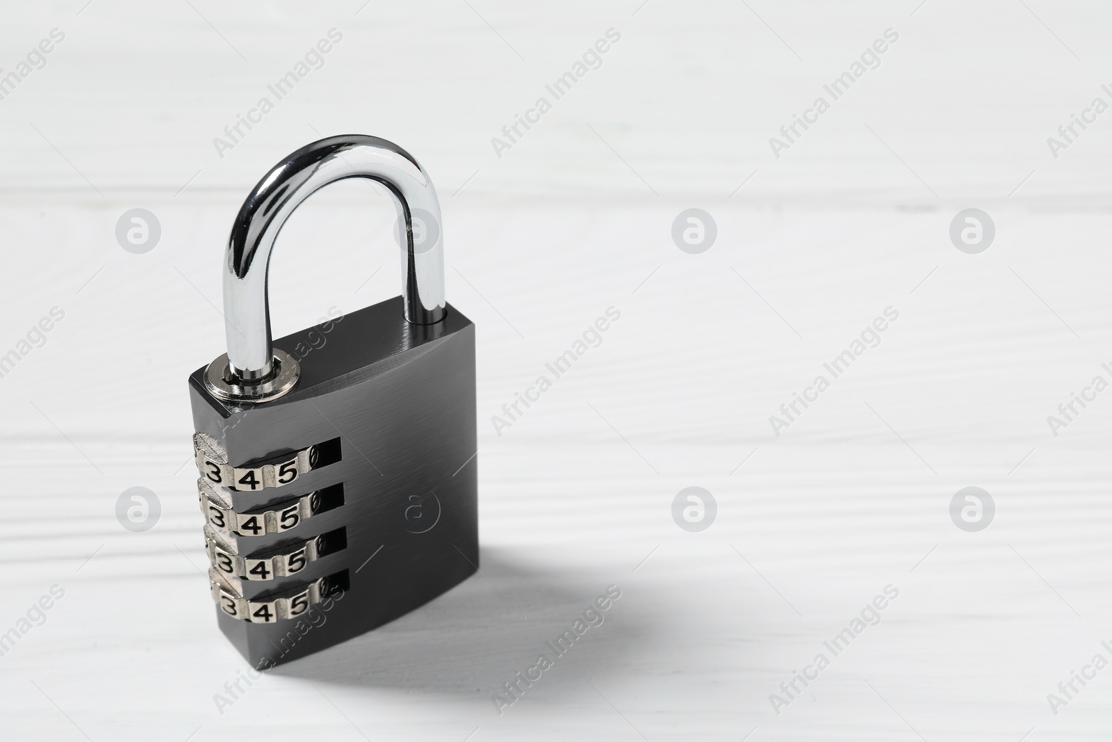 Photo of One steel combination padlock on white wooden table, closeup. Space for text