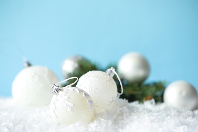 Photo of Beautiful Christmas balls on snow against light blue background. Space for text