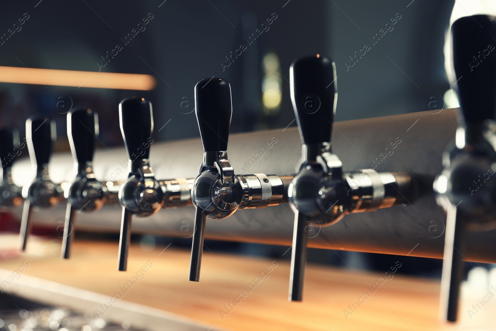 Photo of Row of shiny beer taps in pub, closeup