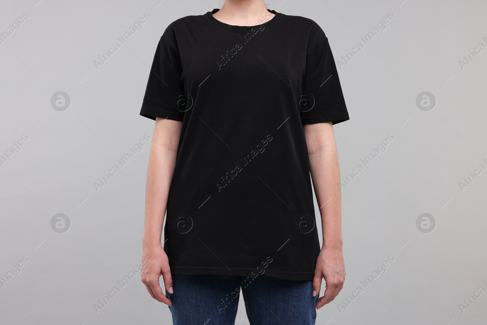 Photo of Woman in stylish black t-shirt light grey on background, closeup