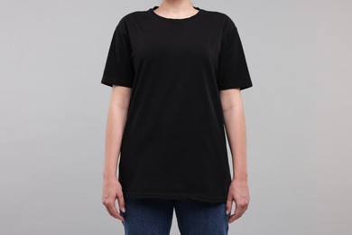 Woman in stylish black t-shirt light grey on background, closeup