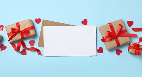 Photo of Blank card, gift boxes and decorative hearts on light blue background, flat lay with space for text. Valentine's Day celebration