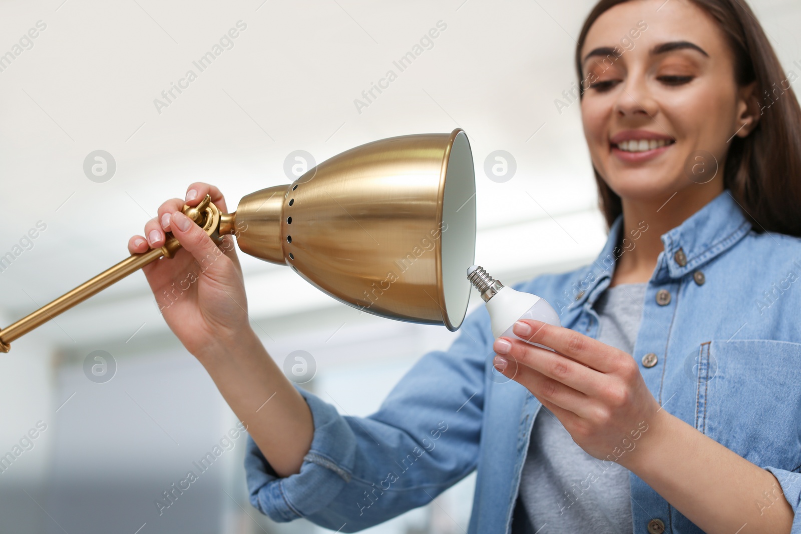 Photo of Woman changing light bulb in lamp indoors