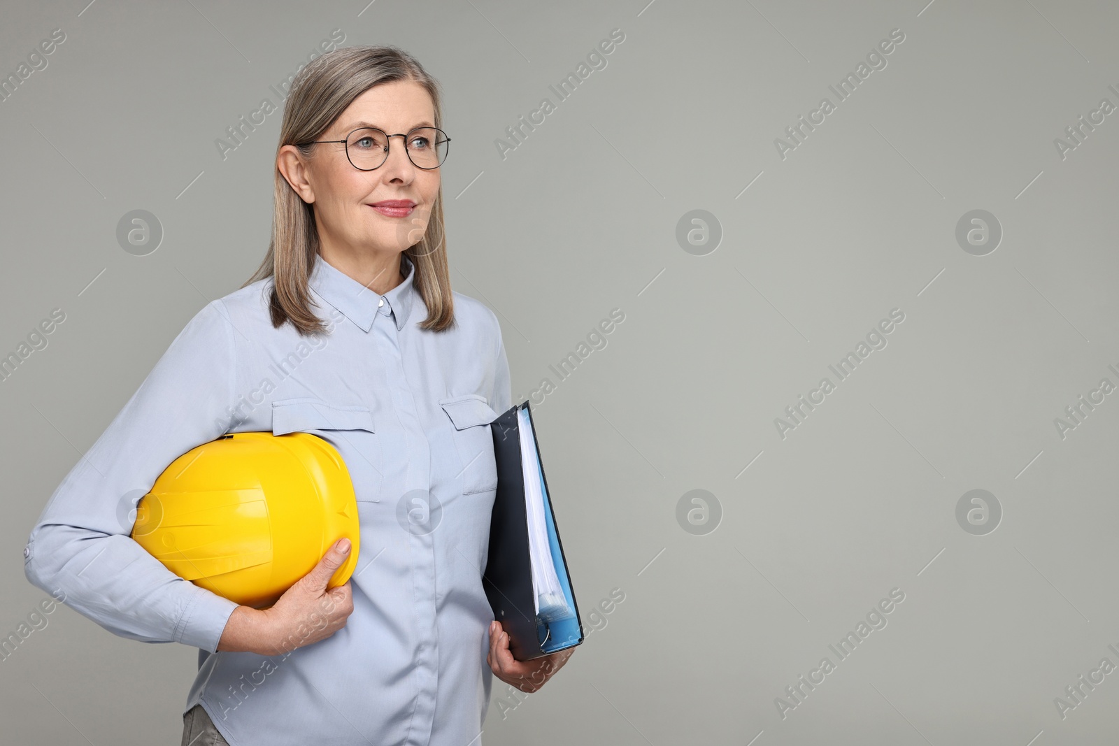 Photo of Architect with hard hat and tube on grey background, space for text