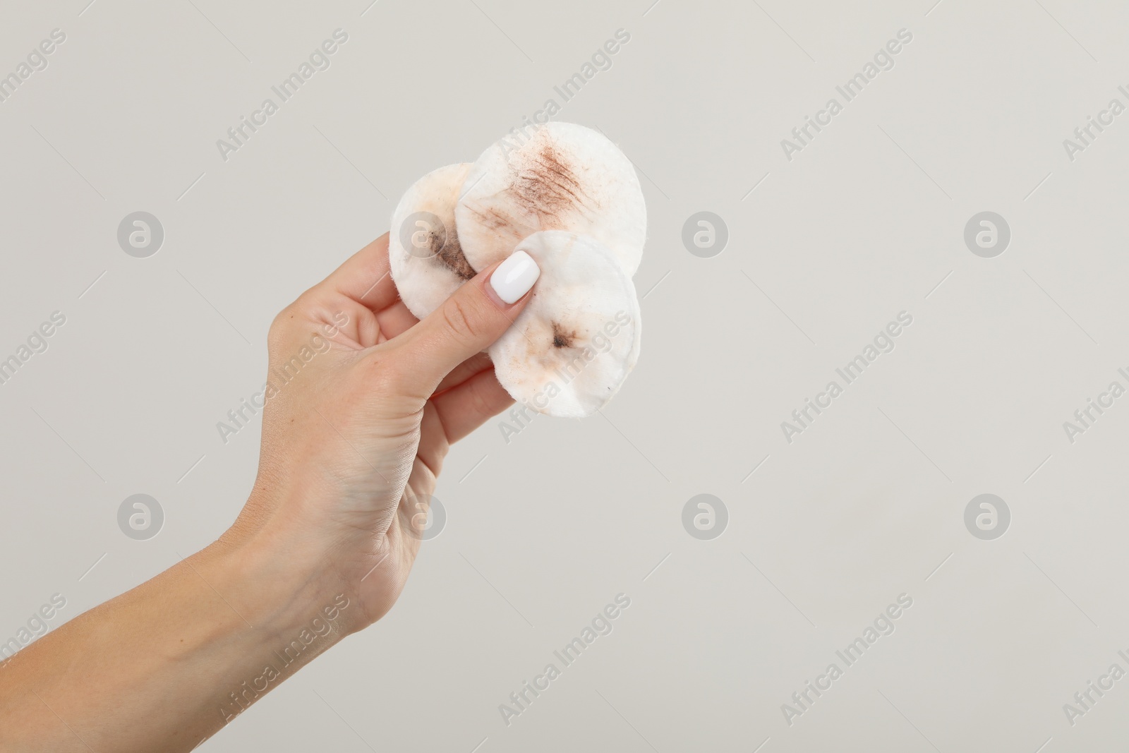 Photo of Woman with dirty cotton pads after removing makeup on light grey background, closeup. Space for text
