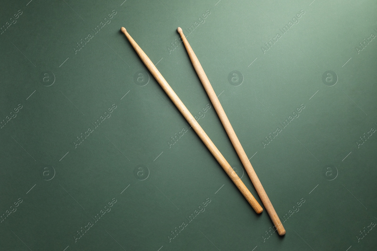 Photo of Two wooden drum sticks on olive background, top view