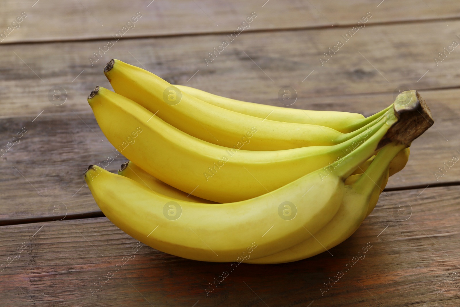 Photo of Bunch of ripe yellow bananas on wooden table