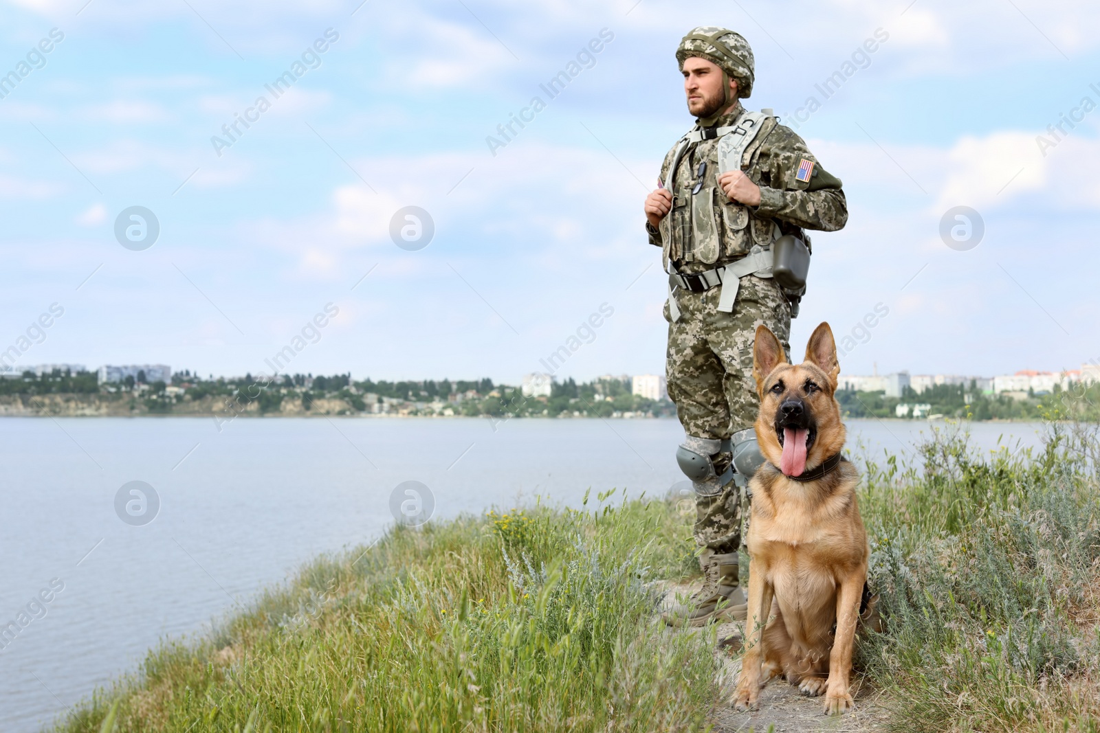 Photo of Man in military uniform with German shepherd dog outdoors