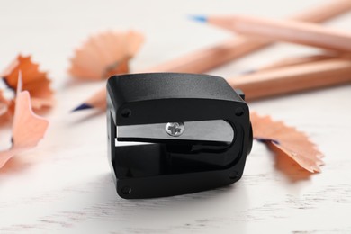 Photo of Black pencil sharpener on white wooden table, closeup