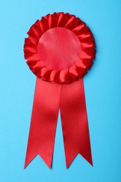 Photo of Red award ribbon on turquoise background, top view