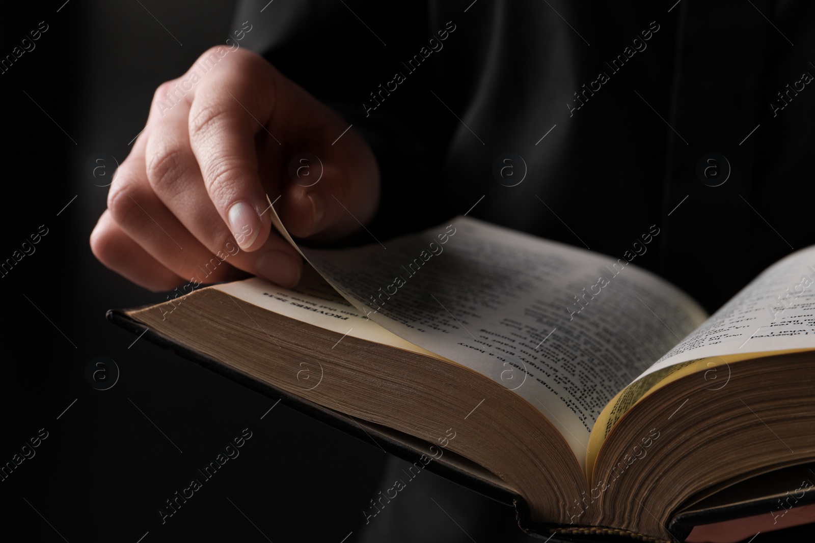 Photo of Woman reading holy Bible on black background, closeup