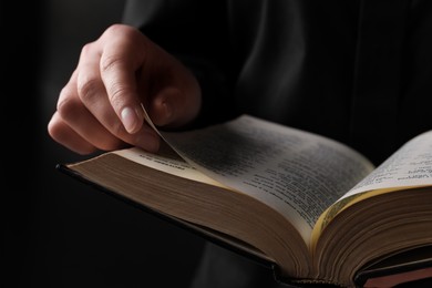 Photo of Woman reading holy Bible on black background, closeup