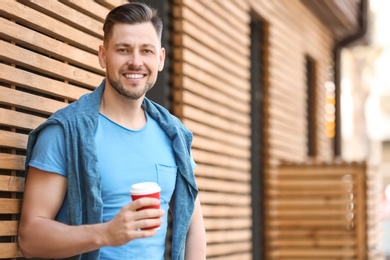 Portrait of young man with cup of coffee outdoors