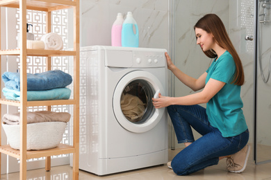 Photo of Woman near washing machine in bathroom. Laundry day