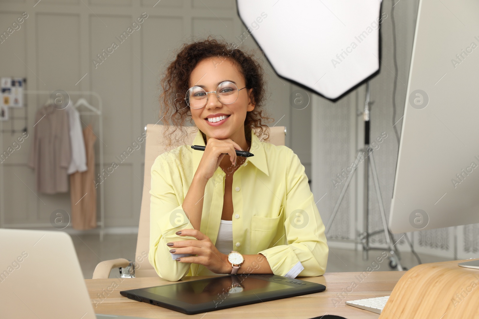 Photo of Professional African American retoucher working with graphic tablet at desk in photo studio