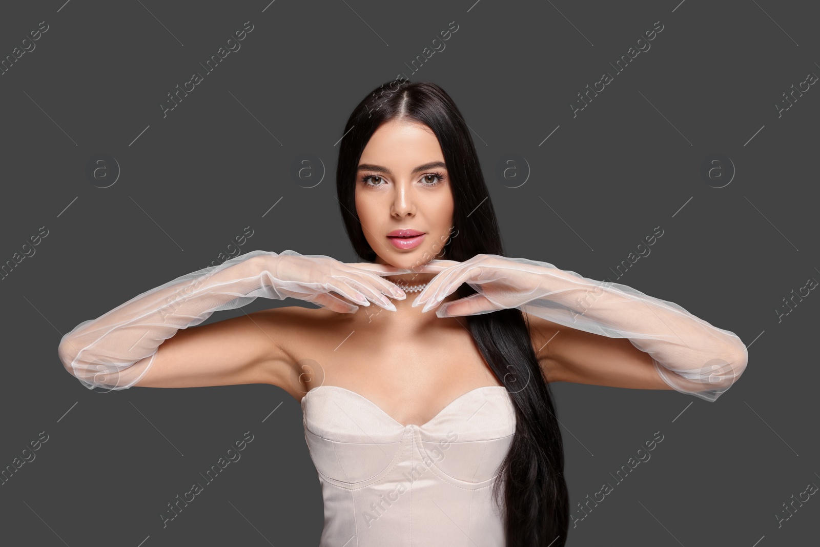 Photo of Portrait of beautiful young woman in evening gloves on black background