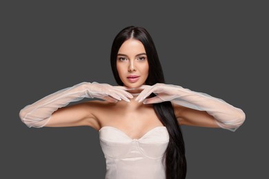 Photo of Portrait of beautiful young woman in evening gloves on black background